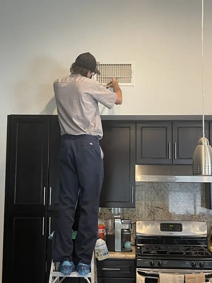 Technician inspecting an air vent during HVAC service in Ironton